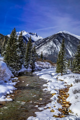 Mountain stream with fresh snow on sunny day