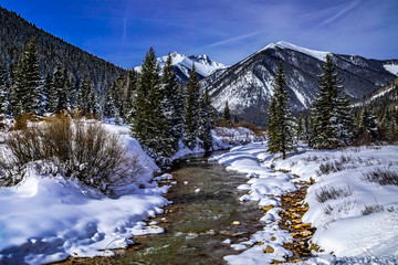 Mountain stream with fresh snow on sunny day