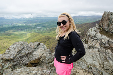 Accomplished smiling woman hiker poses at the summit of LIttle Stony Man, a hike in Shenandoah National Park in Virginia on a foggy day