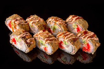 Hot fried Sushi Roll with perch, tobiko caviar, avocado and cheese on black background. Sushi menu. Japanese food. 