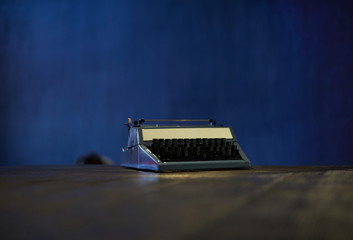 Background image of retro typewriter against blue wall with copy space, concept of writing