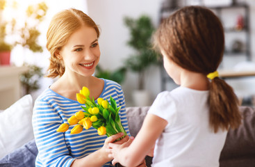 Fototapeta na wymiar happy mother's day! child daughter gives mother a bouquet of flowers to tulip and gift