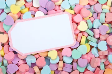 Fotobehang Brightly colored candy hearts, white card with pink border laying on top for copy space. Valentine's Day. © sheilaf2002