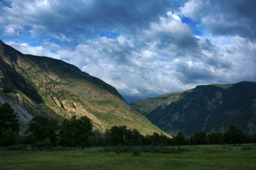 Beautiful clouds in the sky over the mountains in the valley of the Chelushman river in the Altai Republic in Russia.