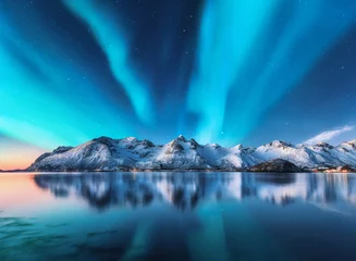 Fotobehang Noorderlicht Noorderlicht en besneeuwde bergen op de Lofoten-eilanden, Noorwegen. Noorderlicht. Sterrenhemel met poollicht en besneeuwde rotsen weerspiegeld in water. Nacht winterlandschap met aurora, zee. Natuur