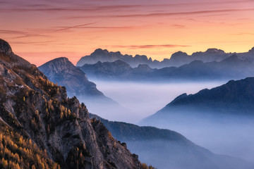 Mountains in fog at beautiful sunset in autumn in Dolomites, Italy. Landscape with alpine mountain...