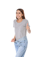 Slim woman in oversized jeans on white background. Weight loss