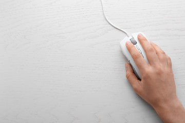 Woman using computer mouse on wooden background, top view. Space for text