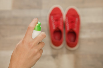 Woman spraying deodorant over pair of shoes at home, closeup. Space for text