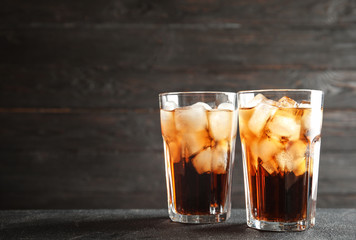 Glasses of refreshing cola with ice cubes on table. Space for text