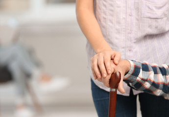 Female caregiver with elderly man, focus on hands. Space for text