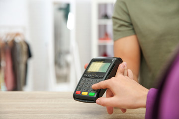 Woman using payment terminal in shop, closeup. Space for text