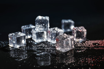 Pile of crystal clear ice cubes on black background