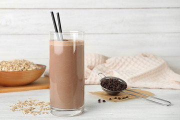 Glass with healthy protein shake and ingredients on table. Space for text