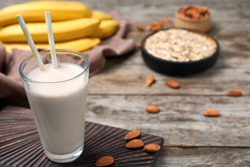 Glass with healthy protein shake and ingredients on table. Space for text