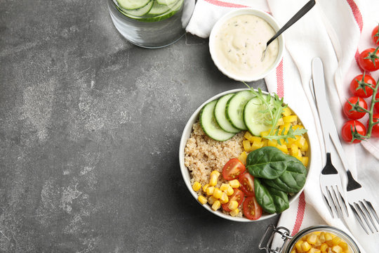 Healthy quinoa salad with vegetables in bowl served on grey table, top view. Space for text