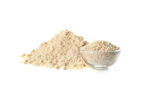 Pile of fresh flour and bowl with sesame seeds isolated on white