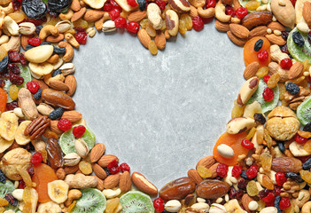 Heart shaped frame of different dried fruits and nuts on color background, top view. Space for text