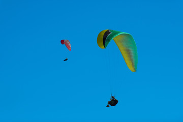 Two paragliders flying in the blue sky. Paragliding in the sky on a bright sunny day