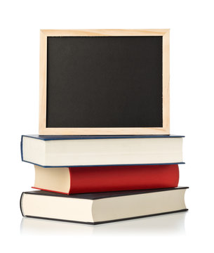 Empty, blank, black chalkboard with stack of books over white