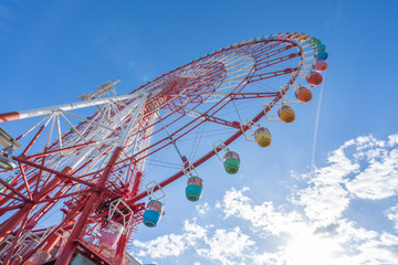 Amazing colorful ferris wheel in amusement park with sunshine blue sky in the morning with copy...
