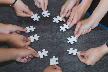 Hands of diverse people assembling jigsaw puzzle, Youth team put pieces together searching for right match, help support in teamwork to find common solution concept, top close up view