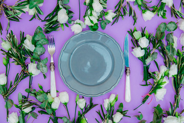 White roses and dishes on purple background