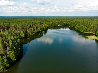 Aerial top down view of beautiful green waters of lake Gela. Birds eye view of scenic emerald lake surrounded by pine forests.
