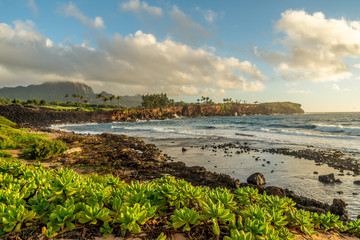 Fototapeta na wymiar Pacific ocean waves crashing against the lithified sand dunes making up the makawehi Bluff, Haupu Mountain in the background, Poipu, Koloa, Kauai, Hawaii