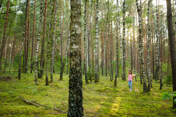 Cute young girl having fun during forest hike on beautiful summer day. Active family leisure.