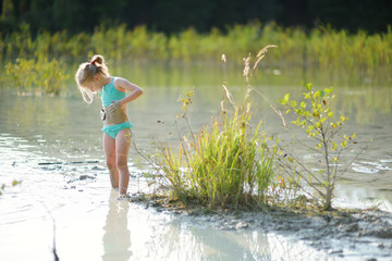 Young girl taking healing mud baths on lake Gela near Vilnius, Lithuania. Child having fun with mud.