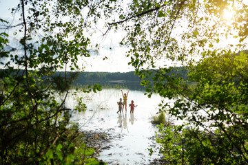 Three young sisters taking healing mud baths on lake Gela near Vilnius, Lithuania. Children having fun with mud.