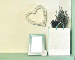 Paper bag with lavender flowers, picture frame with empty blank, heart shape over white wall. Loft life style home decoration on vintage shelf, mockup background