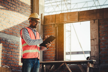 Asian inspector checking structure of new property and taking note in the clipboard for review and fix the house before sell to client