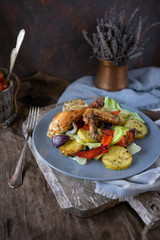 Portion pieces of grilled chicken and vegetable salad on blue ceramic plate