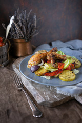 Portion pieces of grilled chicken and vegetable salad on blue ceramic plate