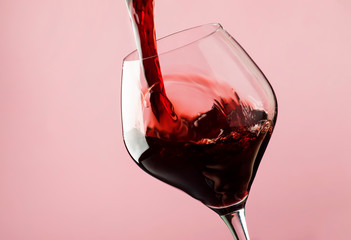 French dry red wine, pours into glass, trendy pink background, space for text, selective focus - obrazy, fototapety, plakaty