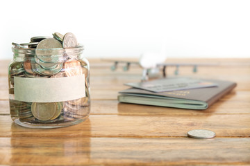 Money savings concept. Collecting money in the money jar for your concept. Money jar with coins, aircraft toy, and passport.