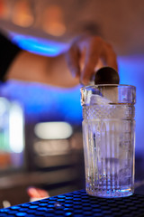 Blurred barman on background creates soft alcoholic coctail at the bar at the night club