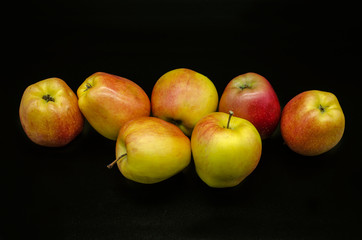 Fototapeta na wymiar Group of beautiful yellow with red spots of ripe apples on a black background