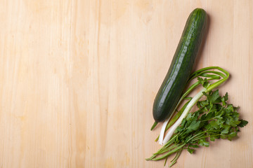 green cucumber with parsley on wooden table, top view template