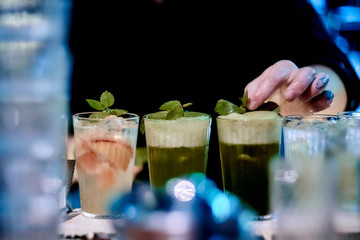 Bluerred foreground and barman hands on background creates soft alcoholic coctail with cola at the bar at the night club