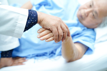 Doctor holding touching hands Asian senior or elderly old lady woman patient with love, care, helping, encourage and empathy at nursing hospital ward : healthy strong medical concept 