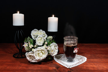 Beautiful bouquet of arranged flowers white candles on a holder, a hot glass of tea on a wooden table. mothers day, Easter, valentines, birthday, Christmas,