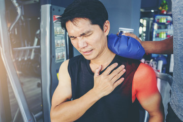 Fit man with shoulder suffering pain has treated with hot compress by his buddy after workout at...