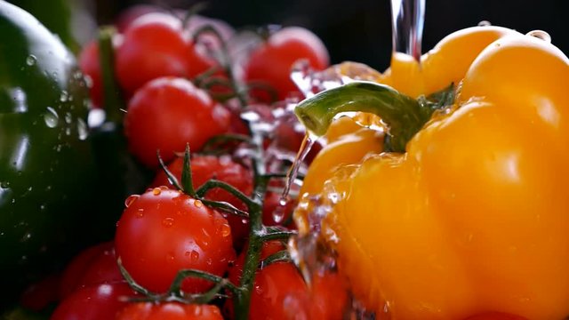 Water stream wash vegetables splashing off a bell pepper in a strainer - closeup, slow motion