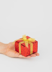 Hand holding red gift box with golden ribbon