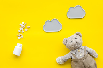 Childhood diseases concept. Treatment of children.Teddy bear toy and pills on yellow background top view space for text