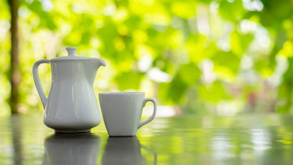 white cup of tea and pot on wooden table in garden