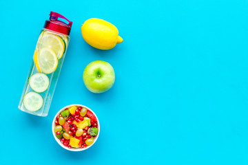 Diet rich in fruits. Slimming diet. Fruit salad near fruit lemon and cucumber water on blue background top view copy space